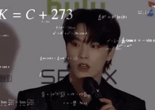 A Young Man Is Holding A Microphone In Front Of A Wall With Math Equations On It . GIF