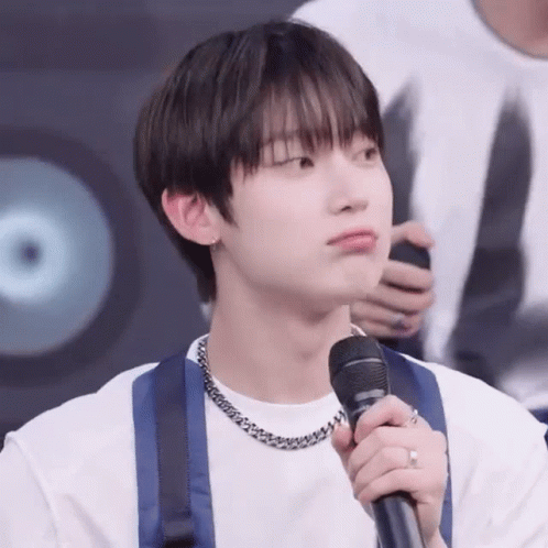 A Young Man Is Holding A Microphone In His Hand . GIF