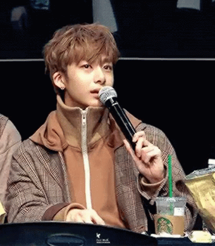 A Young Man Is Holding A Microphone In His Mouth . GIF