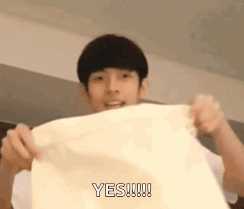 A Young Man Is Holding A Piece Of Paper In His Hands And Says Yes . GIF