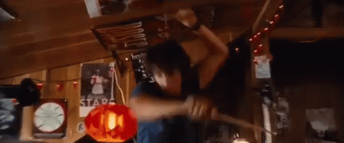 A Young Man Is Holding A Piece Of Wood In His Hands And Making A Funny Face . GIF