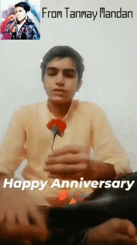 A Young Man Is Holding A Red Rose In Front Of A Picture Of A Man And The Words From Tanmay Mandan Happy Anniversary GIF