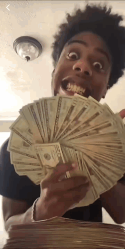 A Young Man Is Holding A Stack Of Money In His Hand . GIF