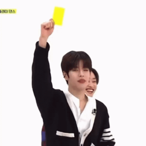 A Young Man Is Holding Up A Yellow Card In A Foreign Language . GIF
