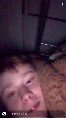 A Young Man Is Laying On A Bed With A Dog And A Snapchat Message That Says " Send A Chat " GIF