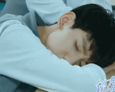 A Young Man Is Laying On A Bed With His Head On His Arm . GIF
