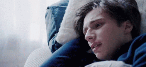 A Young Man Is Laying On A Couch With His Head On A Pillow . GIF