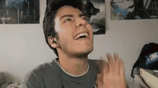 A Young Man Is Making A Funny Face And Clapping His Hands . GIF
