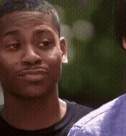 A Young Man Is Making A Funny Face While Looking At Another Man . GIF
