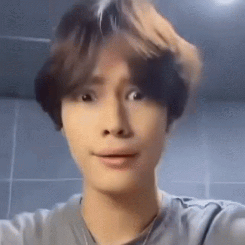 A Young Man Is Making A Funny Face While Taking A Selfie In Front Of A Mirror . GIF