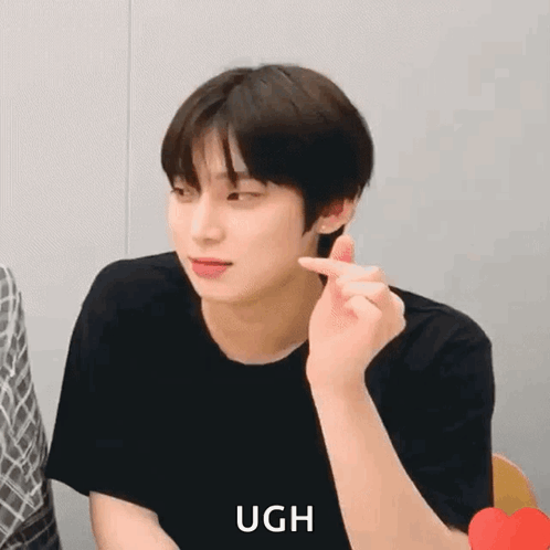 A Young Man Is Making A Heart Shape With His Finger While Wearing A Black Shirt . GIF