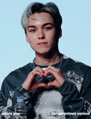 A Young Man Is Making A Heart Shape With His Hands While Holding A Bottle Of Water GIF