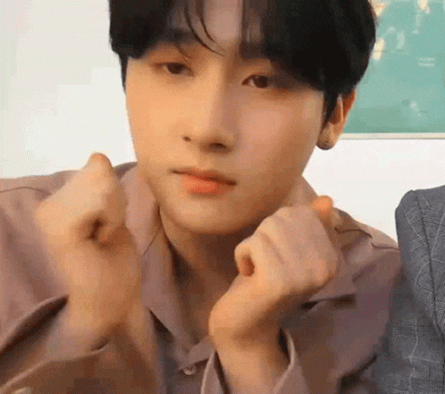 A Young Man Is Making A Heart Shape With His Hands While Looking At The Camera . GIF