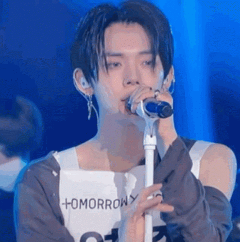 A Young Man Is Singing Into A Microphone While Wearing A Shirt That Says Tomorrow . GIF