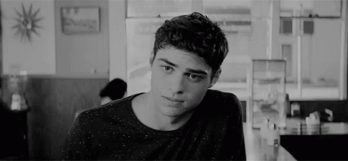 A Young Man Is Sitting At A Table In A Diner Looking At The Camera . GIF