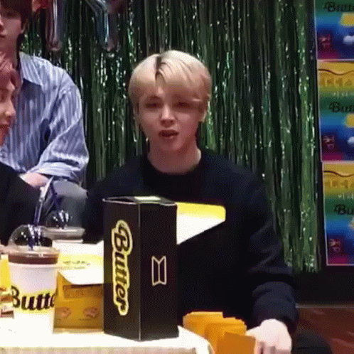 A Young Man Is Sitting At A Table With A Box Of Butter . GIF
