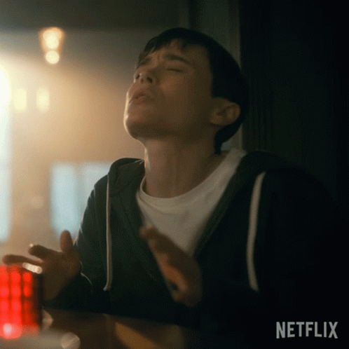 A Young Man Is Sitting At A Table With His Eyes Closed And A Netflix Logo In The Corner . GIF
