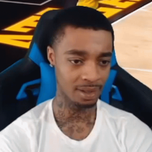 A Young Man Is Sitting In A Blue Chair On A Basketball Court . GIF