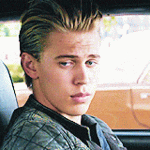 A Young Man Is Sitting In A Car Looking Out The Window GIF