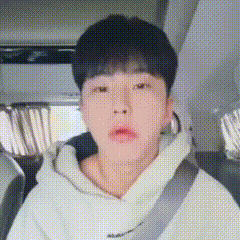 A Young Man Is Sitting In A Car Wearing A Seat Belt And A White Hoodie . GIF