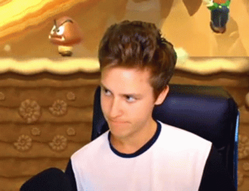 A Young Man Is Sitting In A Chair In Front Of A Video Game Screen And Making A Funny Face . GIF