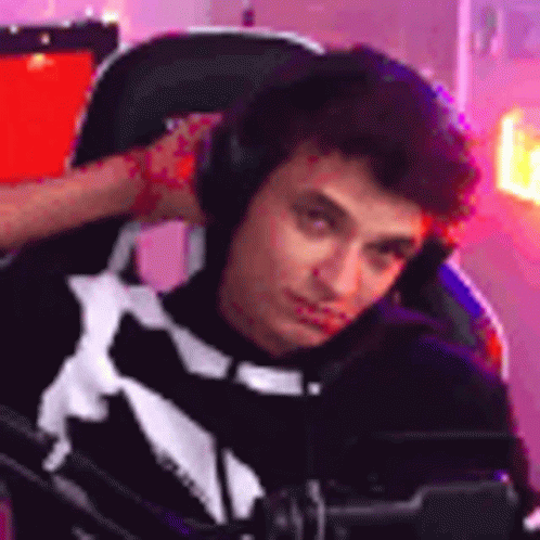 A Young Man Is Sitting In A Chair Wearing Headphones And Looking At The Camera . GIF