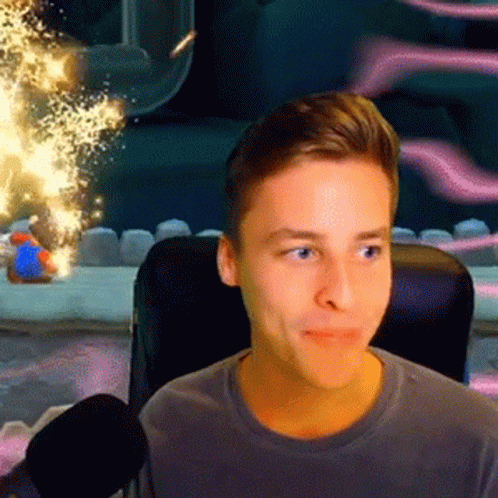 A Young Man Is Sitting In A Chair With A Microphone In Front Of Him Looking At The Camera . GIF
