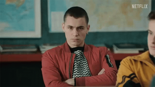 A Young Man Is Sitting In A Classroom With His Arms Crossed . GIF