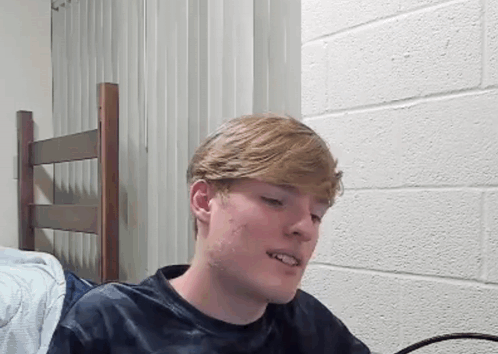 Young Man Sitting In Front Of Brick Wall GIF
