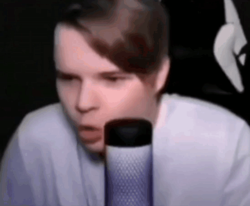 A Young Man Is Sitting In Front Of A Microphone . GIF