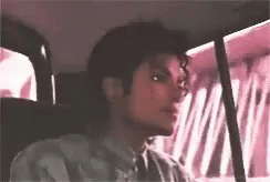 A Young Man Is Sitting In The Back Seat Of A Car . GIF