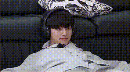 A Young Man Is Sitting On A Couch Wearing Headphones And A Poncho . GIF