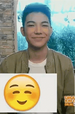 a young man is smiling and holding a picture of a smiley face