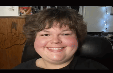A Young Man Is Smiling And Sitting In A Chair GIF