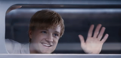 A Young Man Is Smiling And Waving His Hand GIF
