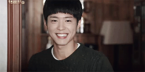 A Young Man Is Smiling For The Camera In A Room . GIF