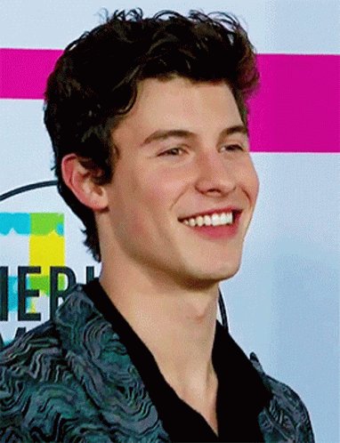 A Young Man Is Smiling In Front Of A Sign That Says ' Ier ' On It GIF