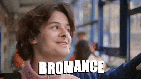 A Young Man Is Smiling In Front Of A Window And The Word Bromance Is Above Him GIF