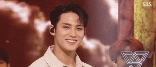 A Young Man Is Smiling On A Stage While Wearing A White Shirt . GIF