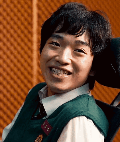 A Young Man Is Smiling While Sitting In A Wheelchair . GIF