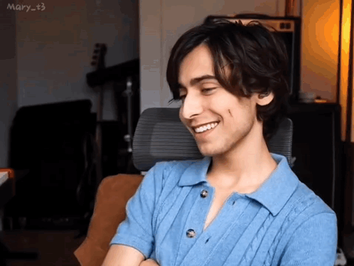 A Young Man Is Smiling While Sitting In An Office Chair . GIF