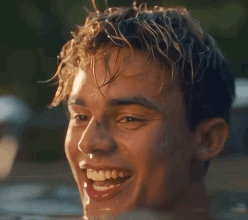 A Young Man Is Smiling While Swimming In A Pool Of Water GIF