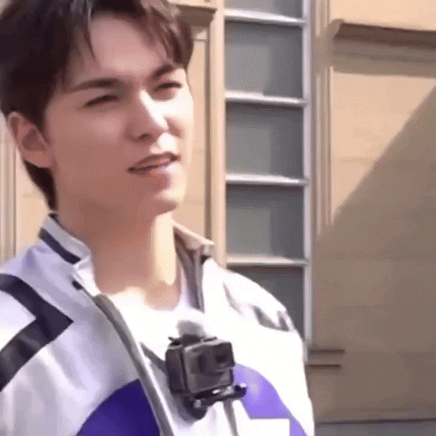 A Young Man Is Standing In Front Of A Building With A Gopro Camera Attached To His Neck . GIF