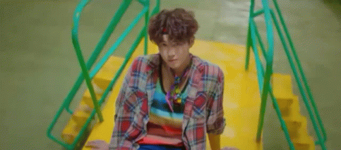 A Young Man Is Standing In Front Of A Palm Tree And Looking At The Camera . GIF