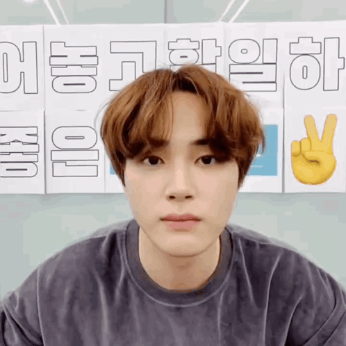 A Young Man Is Standing In Front Of A Sign That Says ' Korean ' On It GIF