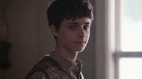 A Young Man Is Standing In Front Of A Window In A Dark Room . GIF