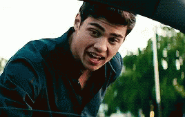A Young Man Is Standing Next To A Car Looking Out The Window . GIF