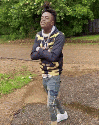 A Young Man Is Standing On A Dirt Road With His Arms Crossed And His Eyes Closed . GIF