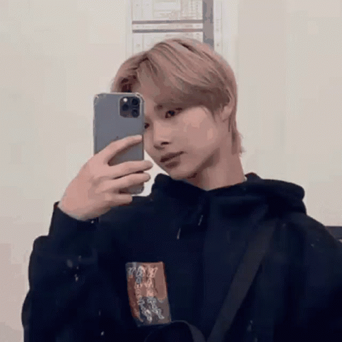 A Young Man Is Taking A Picture Of Himself In A Mirror With His Phone . GIF