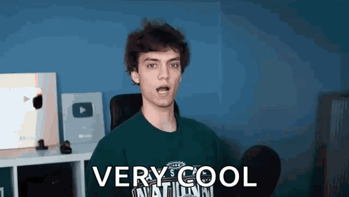 A Young Man Is Wearing A Green Shirt That Says `` Very Cool '' On It . GIF
